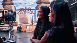 Two women standing behind a camera on a film set